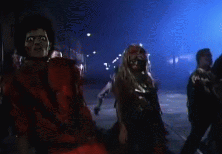 A Man In A Red Mask Is Surrounded By Zombies In A Dark Room GIF