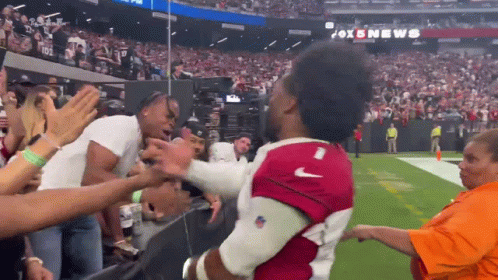 A Man In A Red Nike Jersey Is Being Lifted By A Crowd GIF