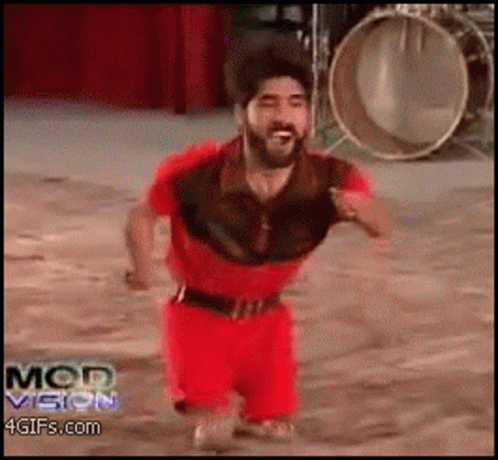 A Man In A Red Outfit Is Running In Front Of A Drum And The Words Mod Vision Are On The Bottom Of The Screen GIF