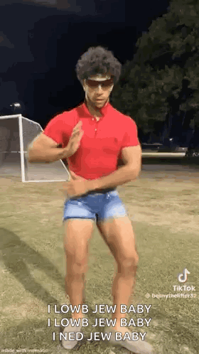 A Man In A Red Polo Shirt And Blue Shorts Is Dancing In A Field . GIF