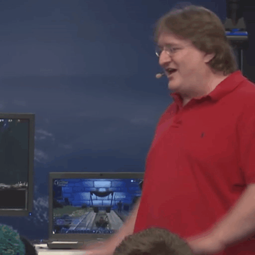 A Man In A Red Polo Shirt Is Standing In Front Of A Computer Screen GIF