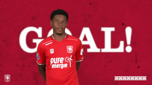 A Man In A Red Pure Energie Shirt Holds His Hands Up In The Air GIF