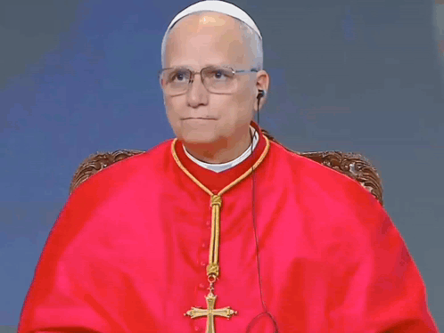 A Man In A Red Robe Has A Cross On His Neck GIF