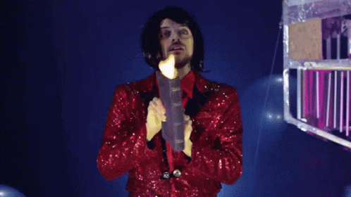 A Man In A Red Sequined Jacket Holds A Book In Front Of His Face GIF