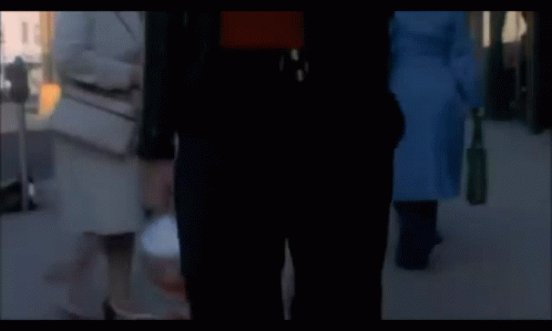 a man in a red shirt and a black jacket is walking down the street