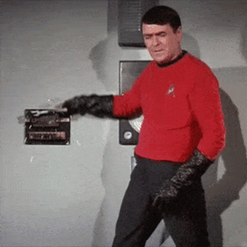 A Man In A Red Shirt And Black Gloves Is Standing In Front Of A Door GIF