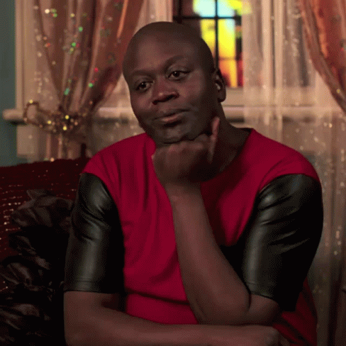 A Man In A Red Shirt And Black Leather Sleeves Is Sitting On A Couch GIF