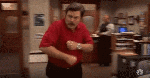 A Man In A Red Shirt And Black Pants Is Dancing In A Room . GIF