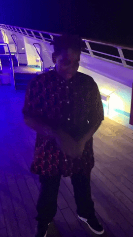 A Man In A Red Shirt And Black Pants Is Standing On A Deck GIF