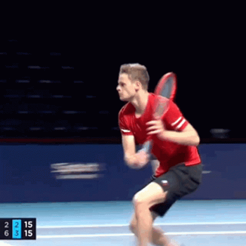 A Man In A Red Shirt And Black Shorts Is Holding A Tennis Racquet On A Tennis Court GIF