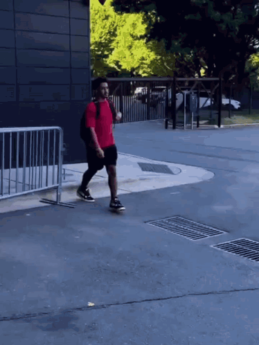 a man in a red shirt and black shorts is walking down a street