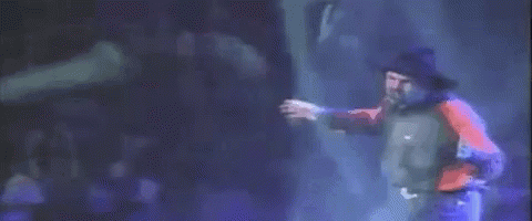A Man In A Red Shirt And Blue Jeans Is Dancing On A Stage . GIF