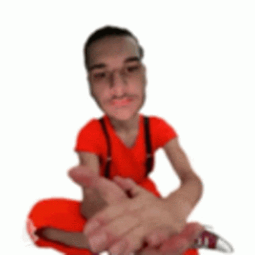 A Man In A Red Shirt And Suspenders Is Sitting On The Floor With His Legs Crossed . GIF