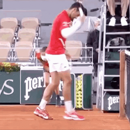 A Man In A Red Shirt And White Shorts Is Standing On A Tennis Court Holding A Tennis Racket . GIF