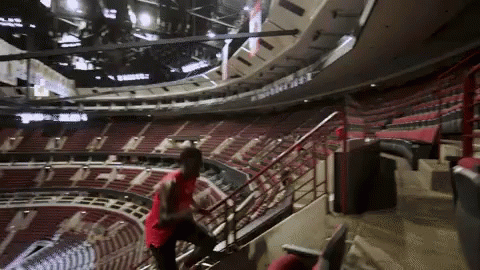 A Man In A Red Shirt Climbs The Stairs Of A Stadium GIF