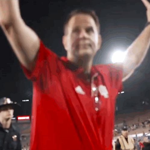 A Man In A Red Shirt Has His Arms Outstretched In The Air GIF