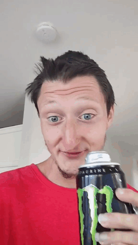 A Man In A Red Shirt Holds A Can Of Monster Energy Drink GIF