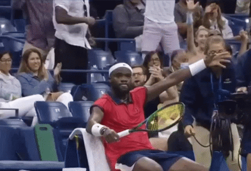 a man in a red shirt holds a tennis racquet in front of a crowd