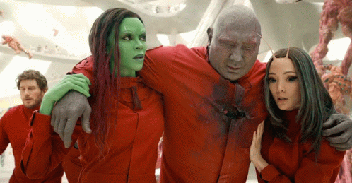 A Man In A Red Shirt Is Being Held By A Woman With Green Hair GIF