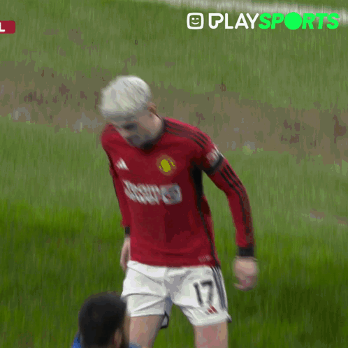 a man in a red shirt is being helped by a man in a yellow jacket with playsports written in green