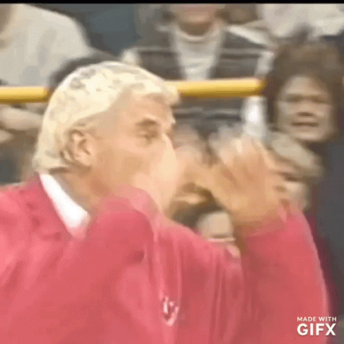 A Man In A Red Shirt Is Blowing A Kiss GIF