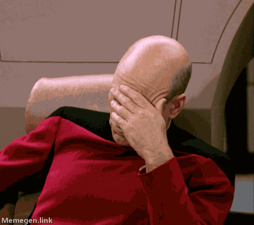 A Man In A Red Shirt Is Covering His Face With His Hands GIF
