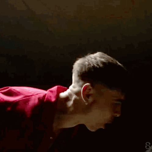 A Man In A Red Shirt Is Dancing In A Dark Room GIF