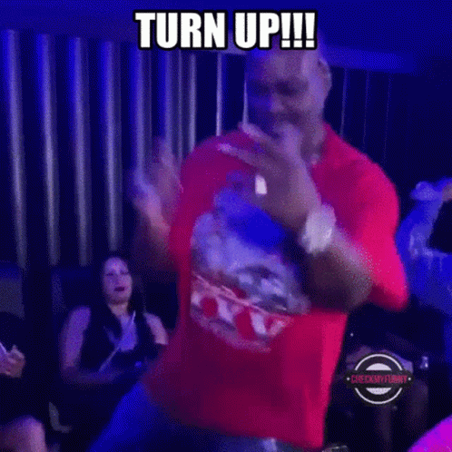 A Man In A Red Shirt Is Dancing In A Dark Room With A Caption That Says Turn Up ! GIF