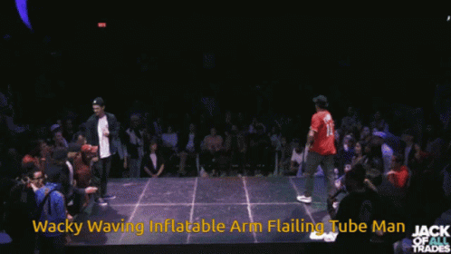 A Man In A Red Shirt Is Dancing In Front Of A Crowd With The Words Wacky Waving Inflatable Arm Flailing Tube Man Written GIF