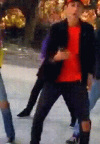 A Man In A Red Shirt Is Dancing On A Ice Rink GIF