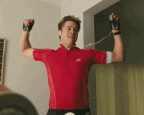 A Man In A Red Shirt Is Flexing His Arm GIF
