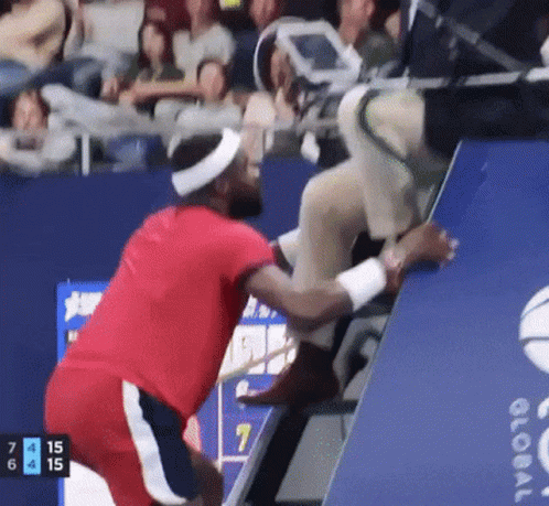 a man in a red shirt is helping another man up a staircase
