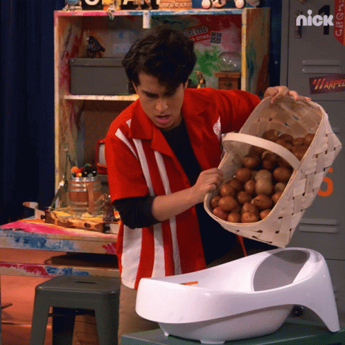 A Man In A Red Shirt Is Holding A Basket Of Potatoes In Front Of A Locker That Says Nick GIF