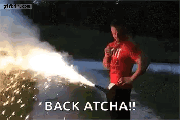 A Man In A Red Shirt Is Holding A Firework Display And Says `` Back Atcha '' . GIF