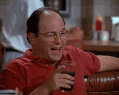 A Man In A Red Shirt Is Holding A Glass Of Soda And Laughing . GIF