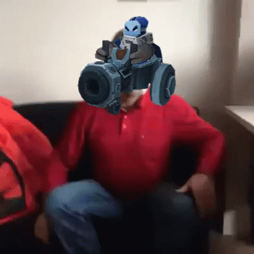 A Man In A Red Shirt Is Holding A Gun In Front Of His Head GIF