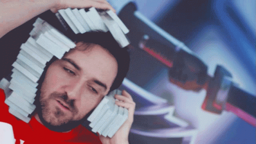 A Man In A Red Shirt Is Holding A Stack Of Cards On Top Of His Head GIF