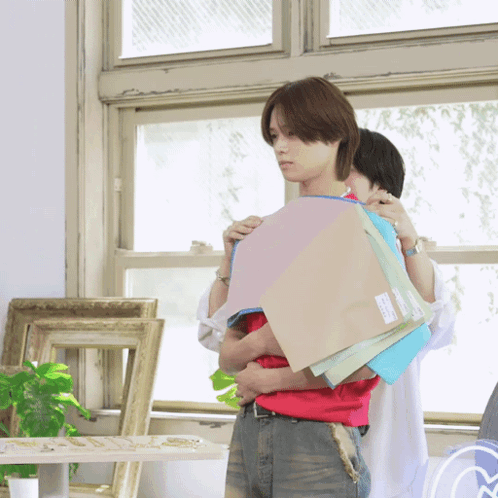 A Man In A Red Shirt Is Holding A Stack Of Paper GIF