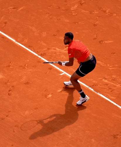 A Man In A Red Shirt Is Holding A Tennis Racquet On A Tennis Court GIF