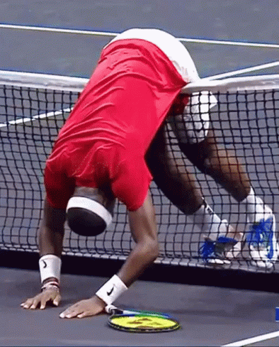 a man in a red shirt is holding a tennis racquet on a tennis court ..