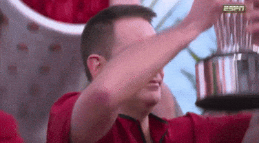 A Man In A Red Shirt Is Holding A Trophy And Covering His Face With His Hand . GIF