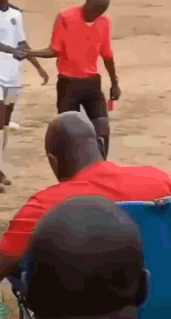 A Man In A Red Shirt Is Holding Another Man 'S Hand While Walking GIF