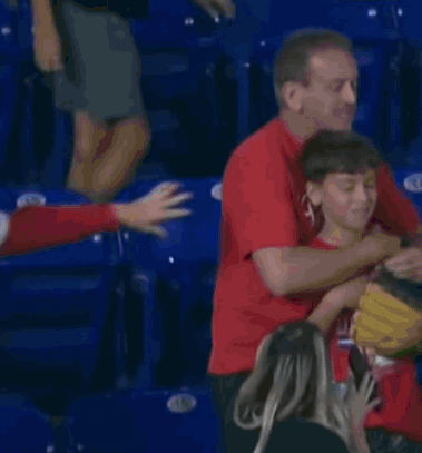A Man In A Red Shirt Is Hugging A Young Boy GIF