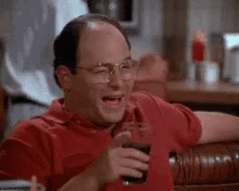 A Man In A Red Shirt Is Laughing While Holding A Glass Of Coke . GIF
