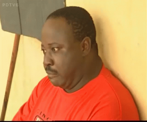 A Man In A Red Shirt Is Leaning Against A Wall With Pdtv6 On The Bottom Right GIF