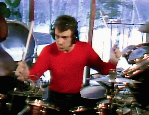 A Man In A Red Shirt Is Playing Drums . GIF