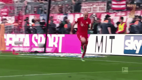 a man in a red shirt is running on a soccer field in front of a sky ad