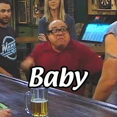 A Man In A Red Shirt Is Sitting At A Bar With A Glass Of Beer In Front Of Him And The Word Baby Written On It GIF