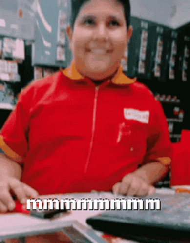 A Man In A Red Shirt Is Sitting At A Table With A Keyboard And A Calculator GIF