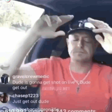 A Man In A Red Shirt Is Sitting In A Car With His Eyes Closed And A Hat On . GIF